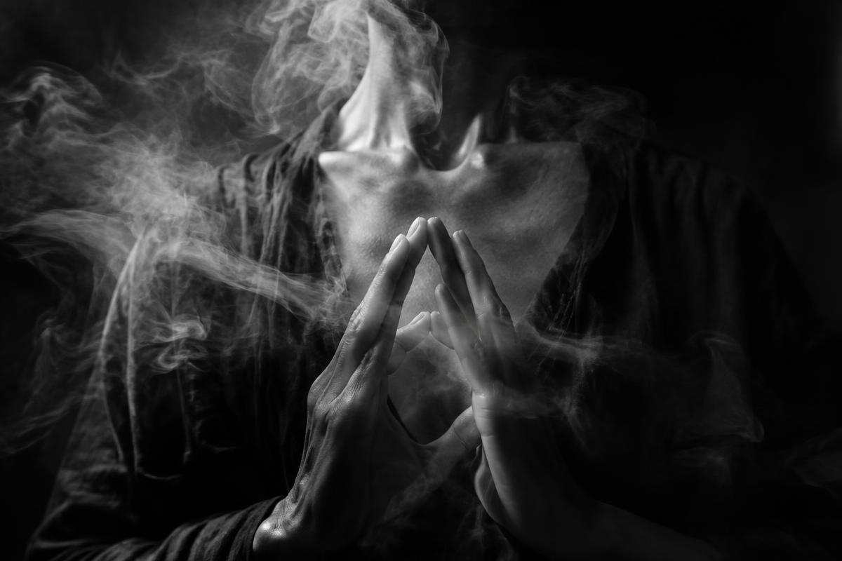 Hands in a pranayama mudra with smoke curling around them, black and white