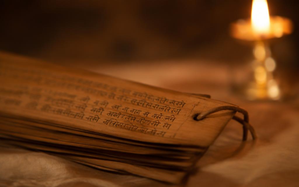 Ancient palm-leaf manuscript pages lit by candlelight